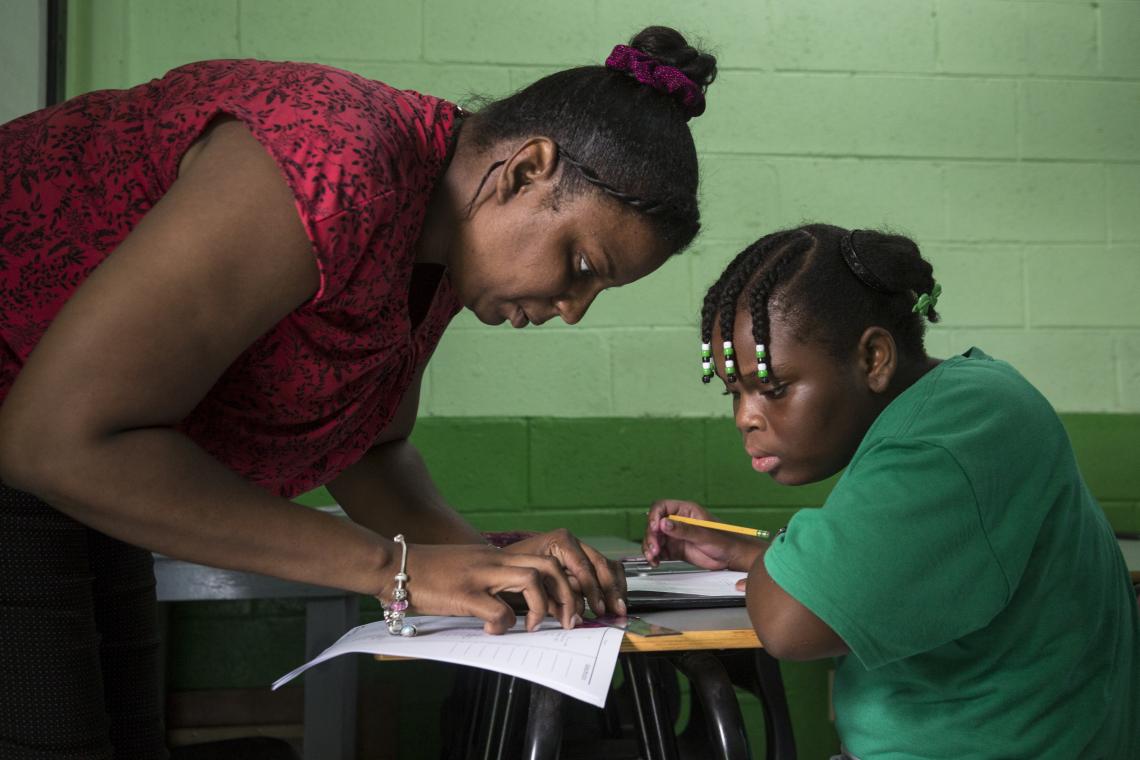 Menina estuda com sua professora na ilha de Antígua, depois que ela e sua família se deslocaram de Barbuda devido à passagem do furacão Irma, em setembro de 2017, na ilha. Foto: UNICEF | UN0345648 | LeMoyne.