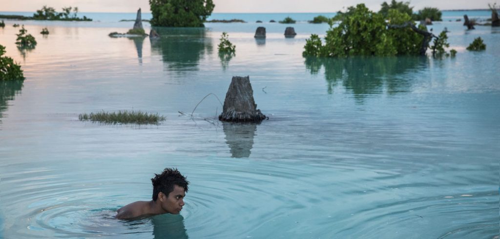 Adolescente de 16 anos nada na área inundada da vila de Aberao, em Kiribati. A ilha do Pacífico é um dos países mais afetados pelo aumento do nível do mar. Foto: UNICEF/Sokhin