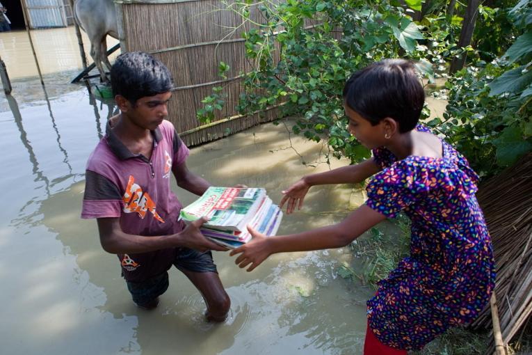 Crianças transportam livros durante as inundações em Bangladesh em 2019. Foto: UNICEF