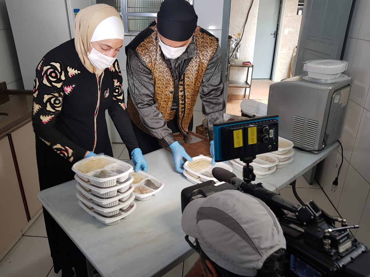 O casal de refugiados sírios Ghazal e Talal prepara marmitas que serão doados para idosos de São Paulo. Foto: Riad Al-Tinawi 