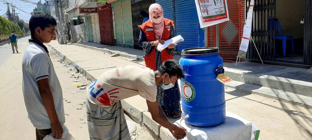 Equipe e voluntários da Sociedade do Crescente Vermelho de Bangladesh promovem lavagem das mãos, com desinfetante em spray, e fornecem alimentos de emergência em meio à pandemia de COVID-19. Foto: Federação Internacional das Sociedades da Cruz Vermelha e do Crescente Vermelho