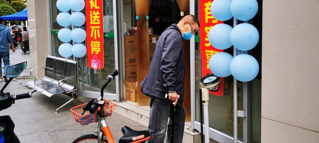 Morador se pesa em balança do lado de fora de farmácia em Wuhan, na China, em 8 de abril, quando o isolamento social da cidade acabou após 76 dias. Balanças fora das farmácias são bastante comuns na China. Foto: Wang Zheng