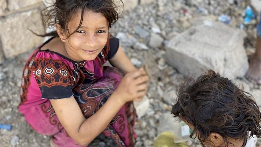 Em fevereiro de 2020, Ipteehal, de 9 anos, brinca com sua irmã do lado de fora do prédio inacabado onde moram com outras famílias deslocadas em Al Mukalla, no Iêmen. Foto: ACNUR/Marie-Joëlle Jean-Charles