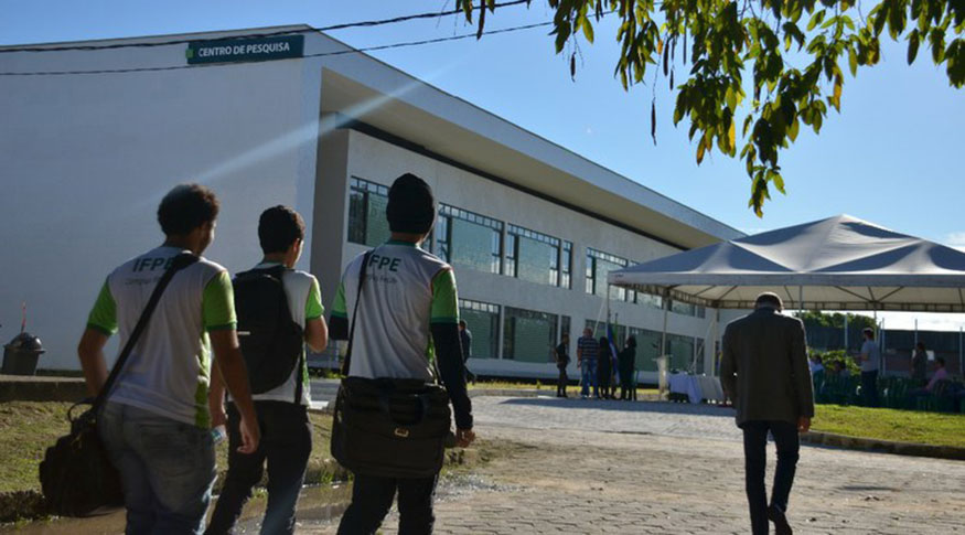 #PraCegoVer A foto mostra 3 alunos de costas com a camiseta da Instituto Federal de Pernambuco chegando no Centro de pesquisas