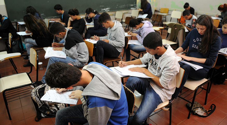 #PraCegoVer jovens em sala de aula fazendo prova