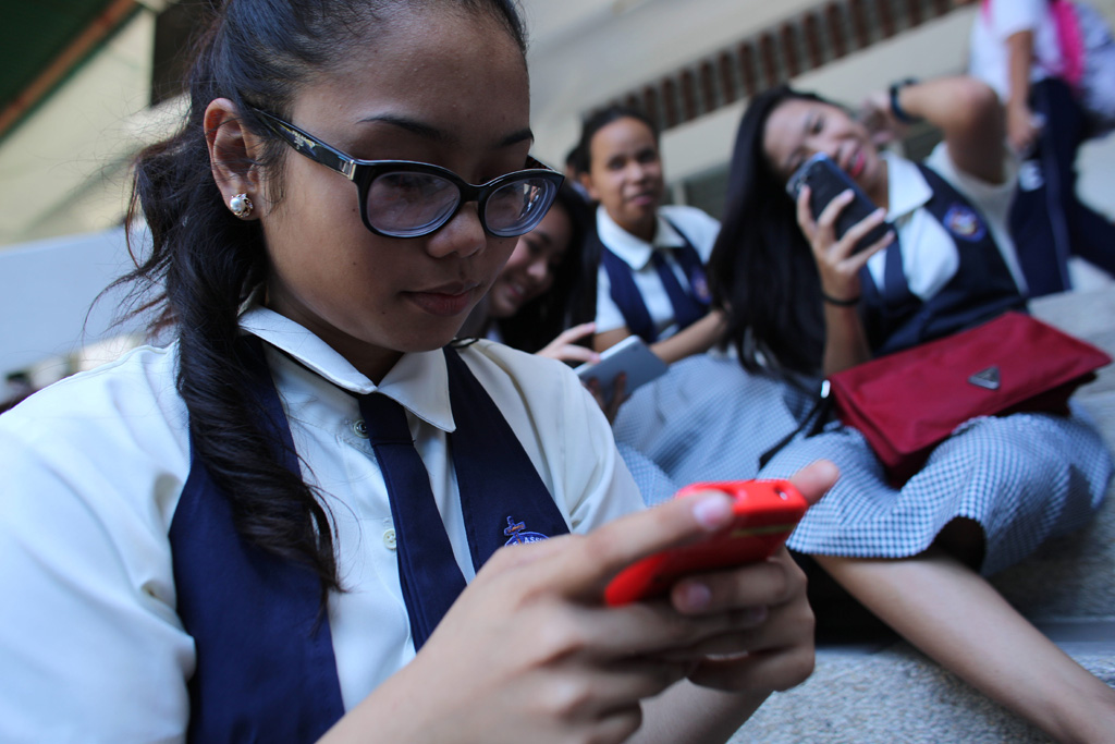 Estudantes mexem no celular durante recreio em escola de Cebu, nas Filipinas. Foto: UNICEF/Estey