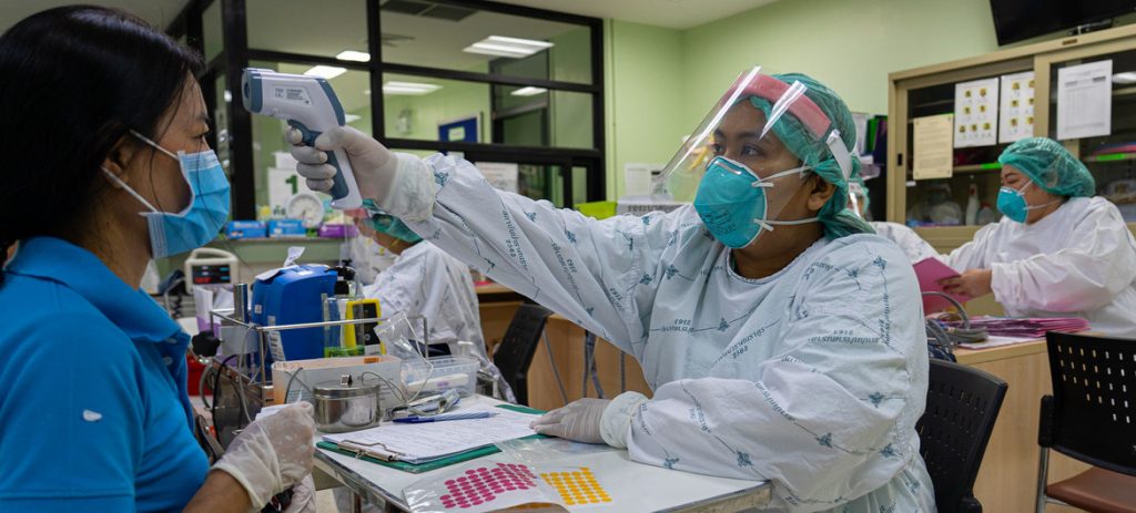 Profissional de saúde verifica a temperatura de paciente em hospital na província de Nonthaburi, Tailândia. Foto: ONU Mulheres/Pathumporn Thongking