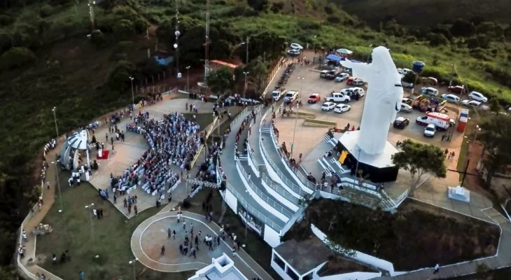 Indígenas ocupam praça em frente à uma estátua construída em território sagrado. A imagem vista de cima mostra o entorno da obra.