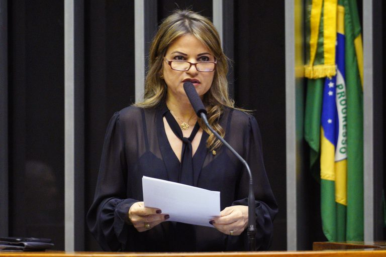 Deputada Flávia Morais discursa no Plenário da Câmara. Ela usa uma blusa preta e óculos e segura um papel