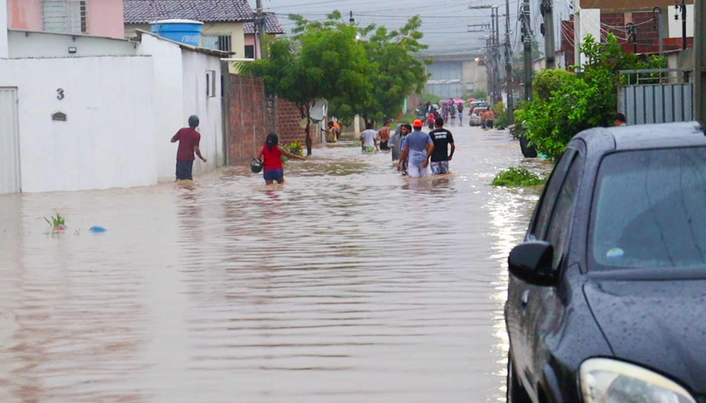 Pessoas andam em ruas alagadas pelas fortes chuvas na Bahia