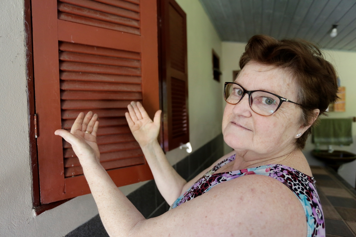 Fátima é uma senhora na faixa dos 60 anos, com cabelos e olhos castanhos; na foto ela mostra as mãos sujas de preto, por causa da exploração de carvão que acontece em um local próximo à sua residência