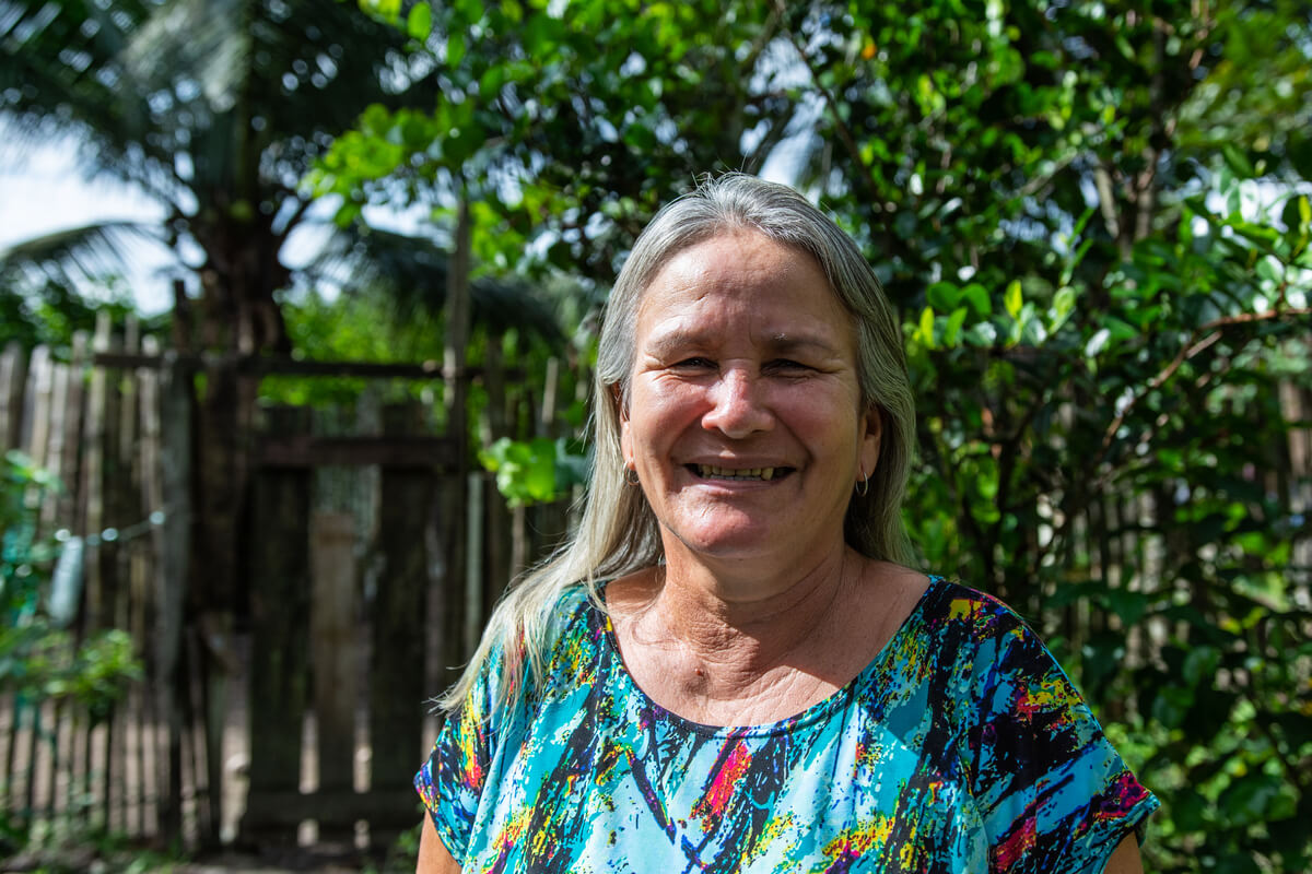 Mulher com cabelos grisalhos sorri para a câmera