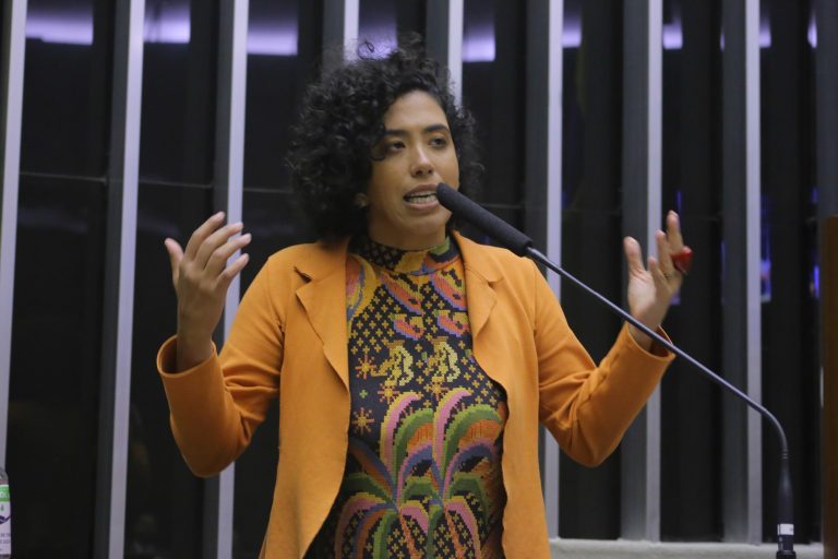 Deputada Talíria Petrone discursa no Plenário da Câmara. Ela é negra, tem cabelo crespo e usa um blazer laranja