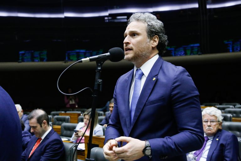 Deputado Fred Costa discursa no Plenário da Câmara. Ele é branco e usa um terno azul escuro