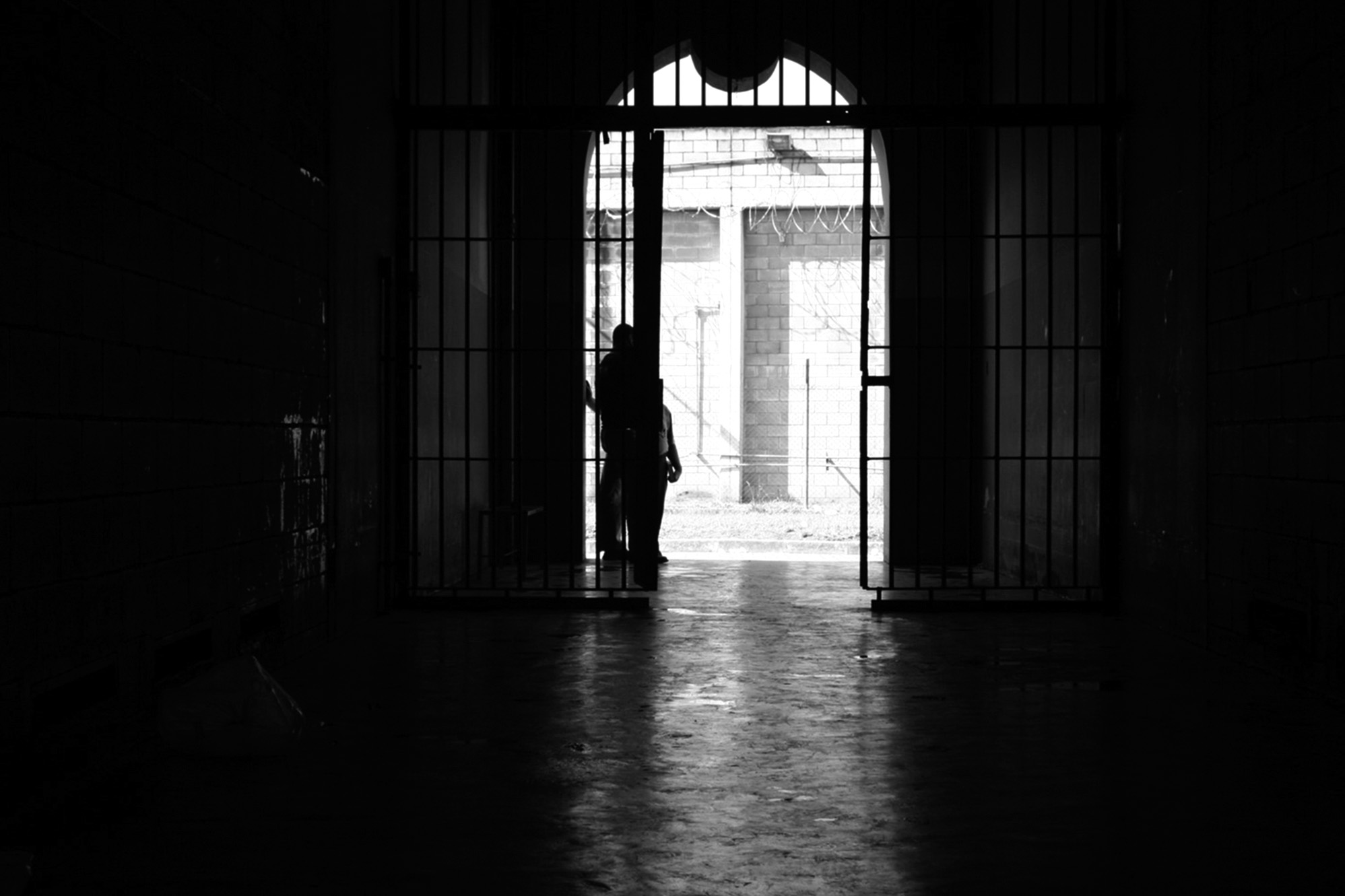 Foto em preto e branco de pessoas na frente de um portão gradeado