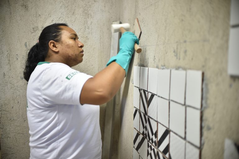 Uma mulher assenta azulejos numa parede