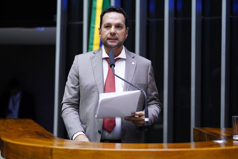 Deputado Josenildo fala ao microfone. Ele é um homem branco, tem cabelo, barba e bigodes escuros e usa um terno cinza claro