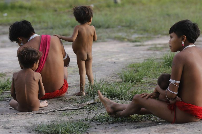 Mulheres e crianças yanomami sentadas no chão