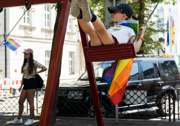 Jovem brinca no balanço durante uma marcha de orgulho na Europa