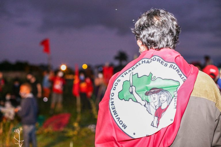 Um homem está com uma bandeira vermelha pendurada nas costas