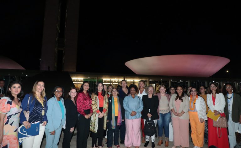 Deputadas em frente da cúpula da Câmara iluminada de lilás