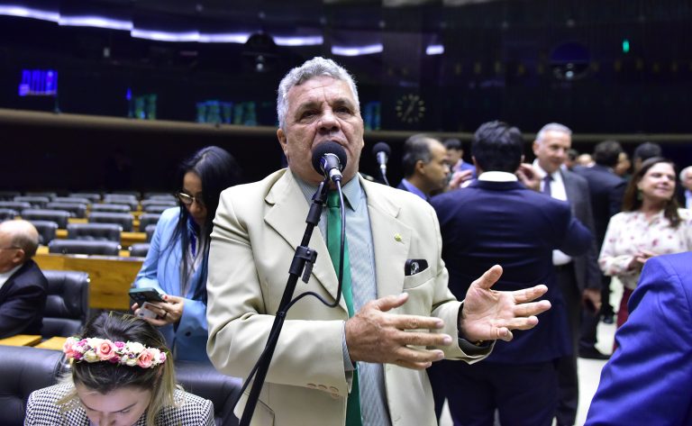 Deputado Alberto Fraga fala ao microfone. Ele é claro, tem o cabelo grisalho, usa terno claro com gravata verde. Ao fundo, vários deputados estão em pé conversando