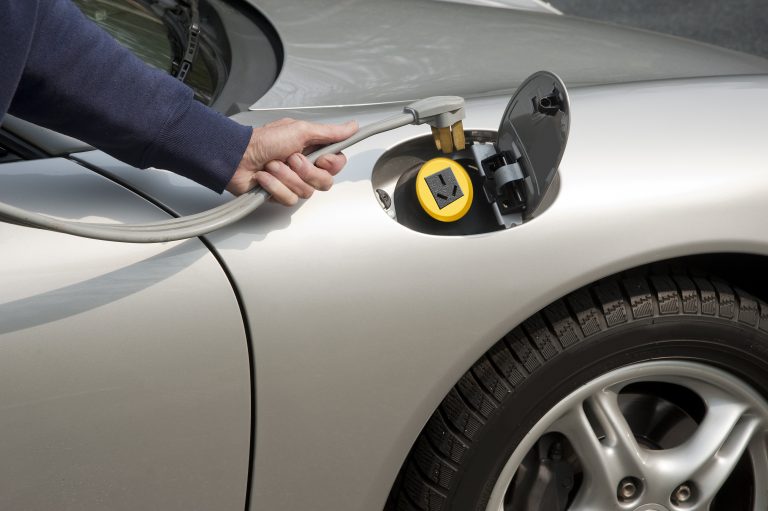 Uma pessoa conceta um plugue num carro elétrico para abastecê-lo