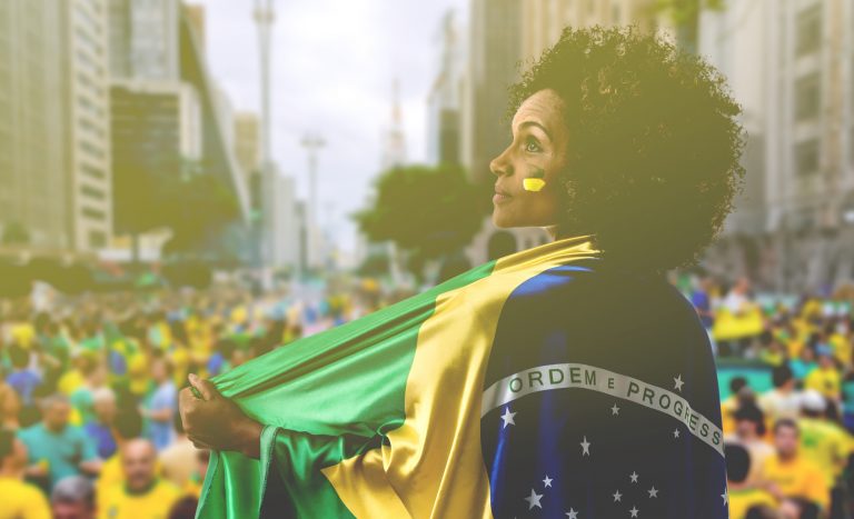 Mulher negra está envolvida numa bandeira do Brasil