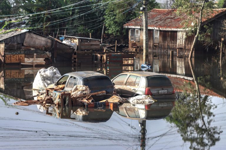 Dois carros estão submersos numa rua inundada