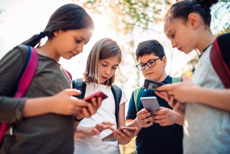 Crianças reunidas mexendo no celular
